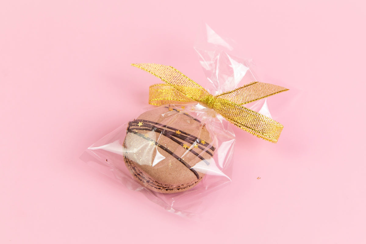 A single Trophy macaron in a clear ribbon-tied gift bag