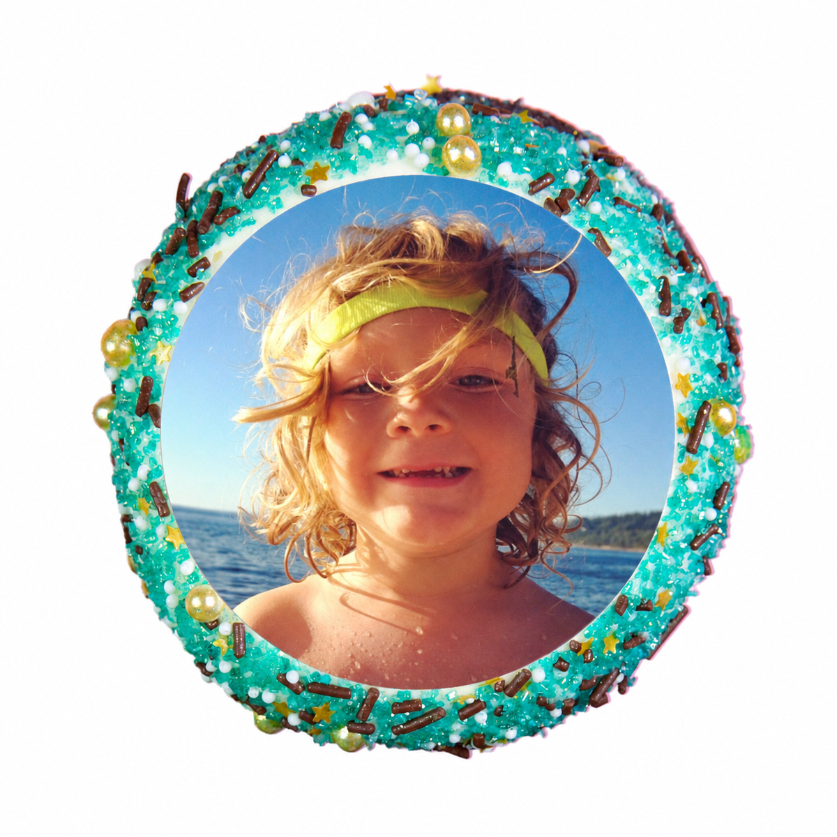 Photo cupcake with aqua and gold sprinkles and a child with windswept curls at the beach