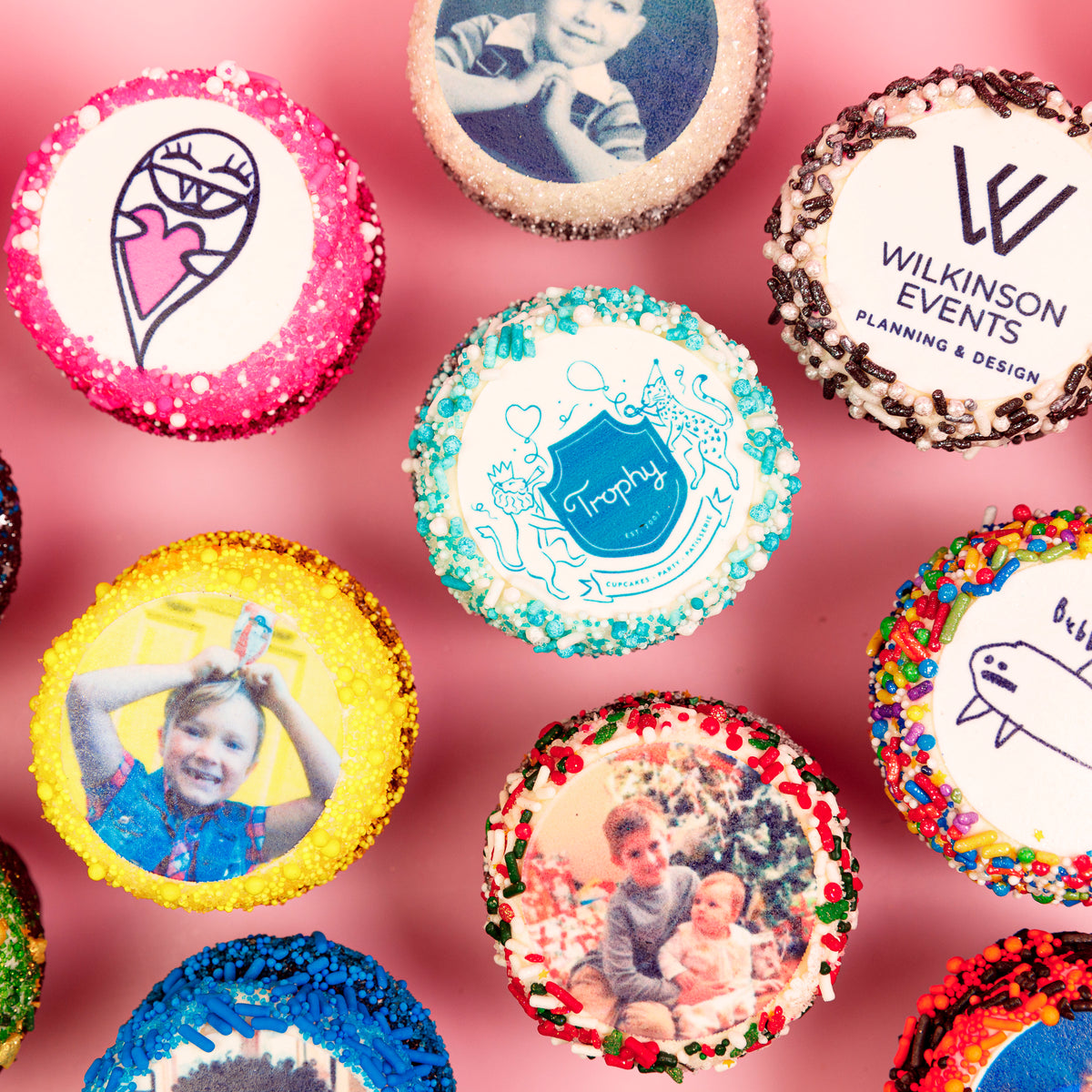 Custom Photo Cupcakes overhead with assorted printed photos, logos and drawings and colorful sprinkle borders