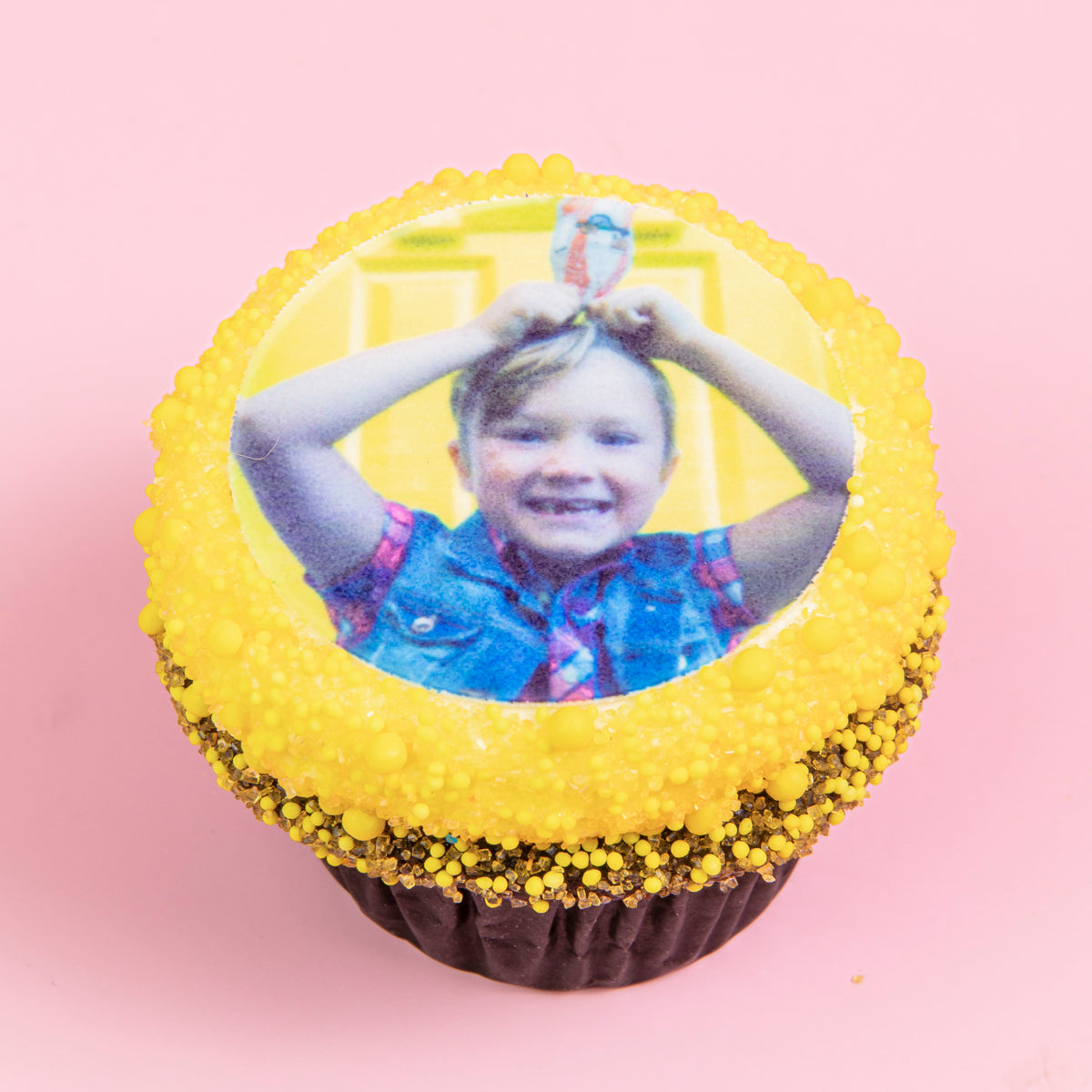 Custom Photo Cupcakes cupcake with a child's photo on top and a yellow sprinkle border on pink