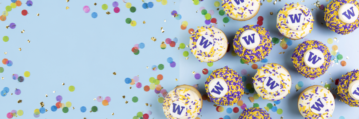 Overhead view of UW W cupcakes with purple and gold sprinkles and colorful confetti on a light blue table