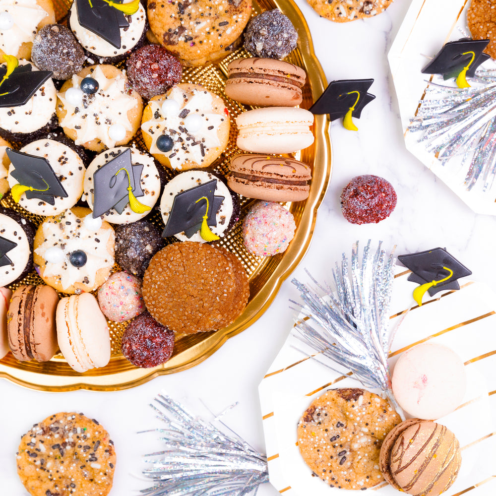 Gold tray of mini cupcakes with graduation cap toppers, macarons, truffles and cookies