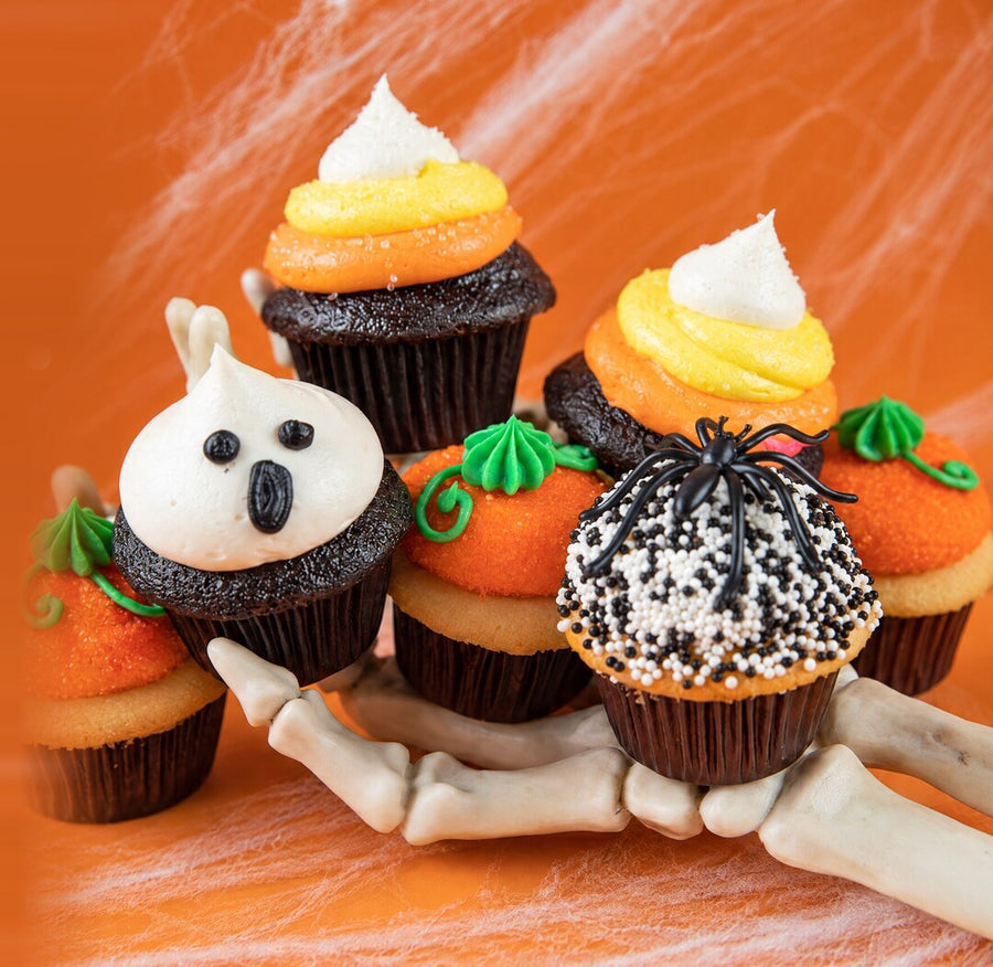 Six Halloween cupcakes held in a skeleton hand