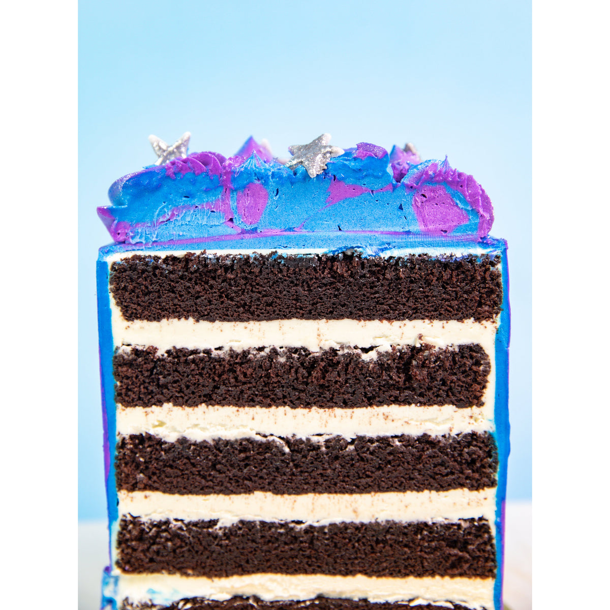 Galaxy Cake cut open showing layers of chocolate cake and white buttercream